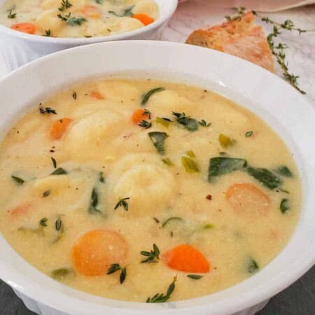 A warm bowl of gnocchi soup with tender carrots, blended together in a white bowl