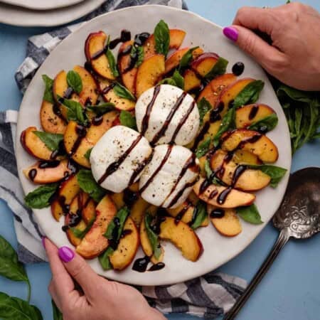 Peach caprese salad topped with balsamic vinegar on a white plate, a no-cook dinner.