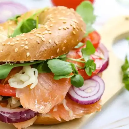 Smoked salmon bagel topped with veggies on a cutting board
