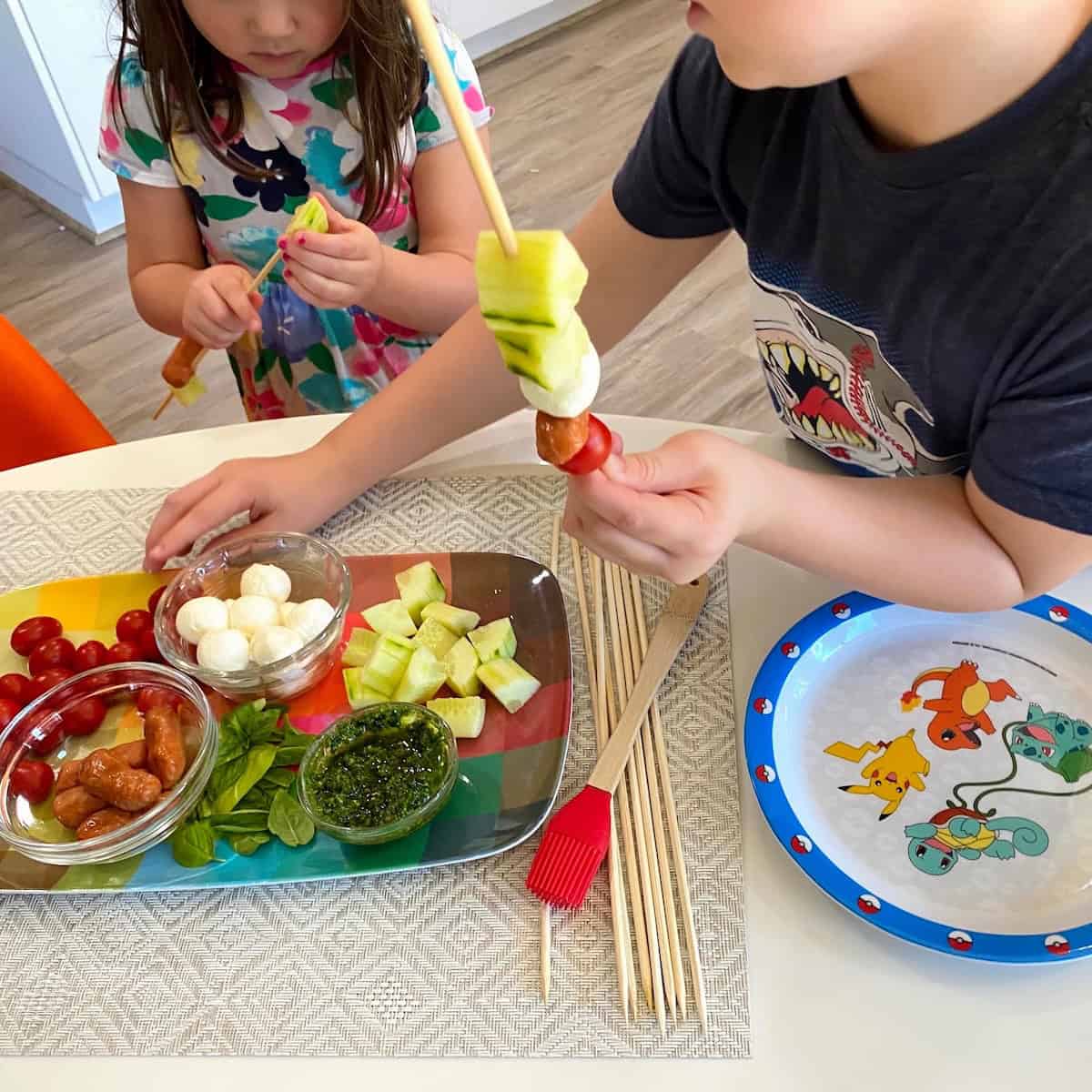 Two kids assembling caprese kabobs.